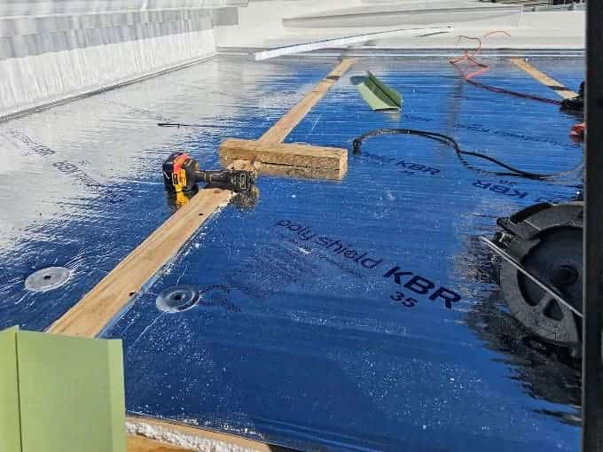 Pressure-treated framed perimeter with 2x4s anchored with 3 inch screws every 1 foot. Installed 4 by 12 foot foil faced insulation board fastened with 3 inch screws and 3 inch washers before TPO membrane installation.