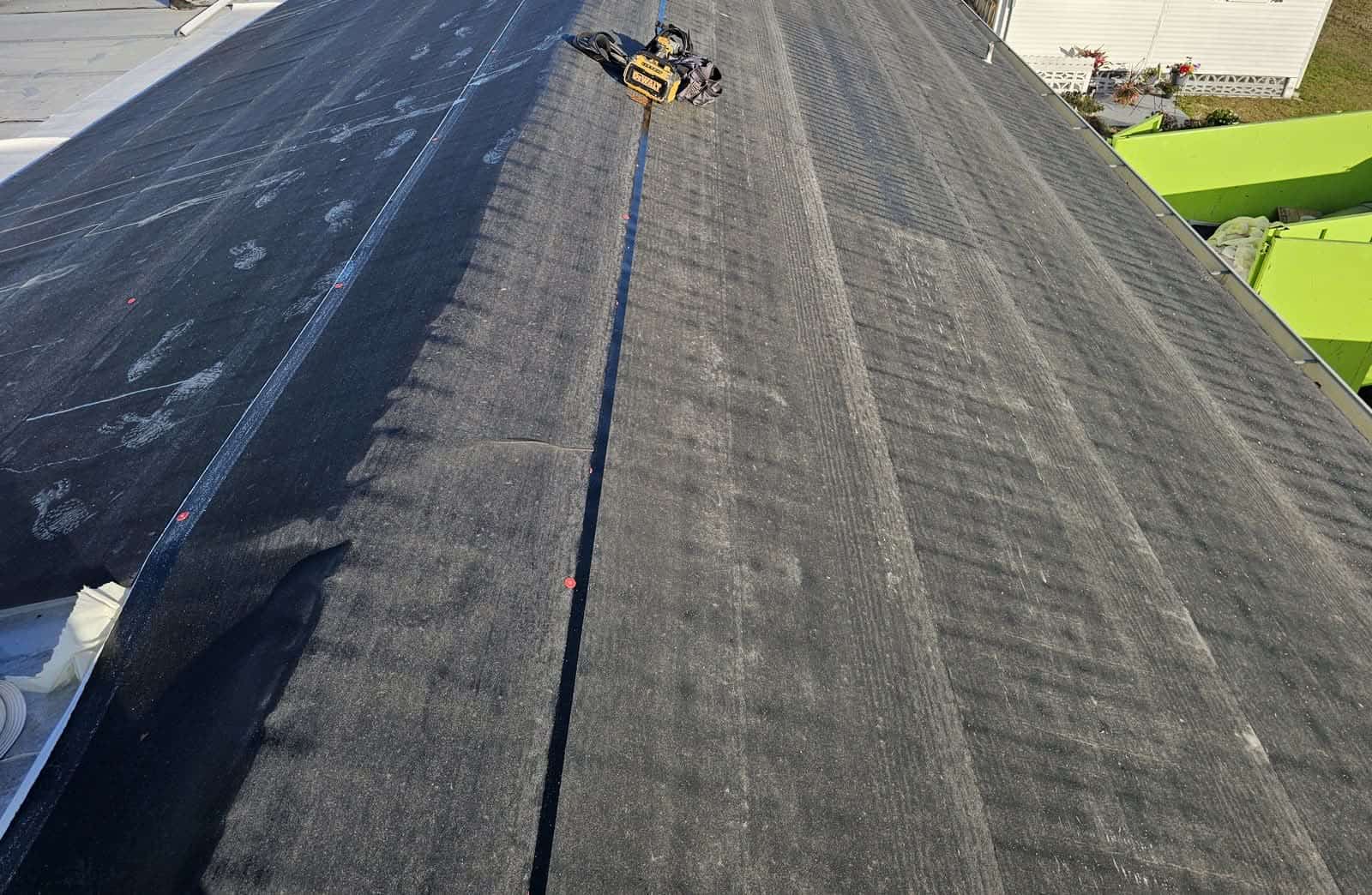 New synthetic underlayment rolled and fastened across the full roof deck with chalk lines snapped